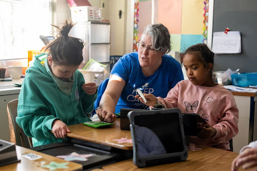 teacher working with students as a desk table