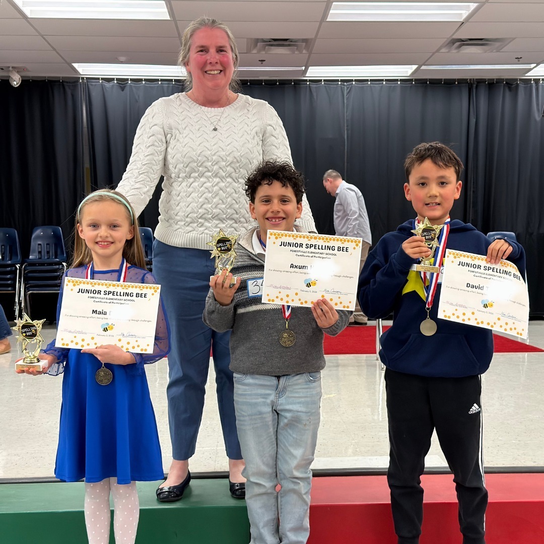 Three students standing with the school principal after winning the spelling bee