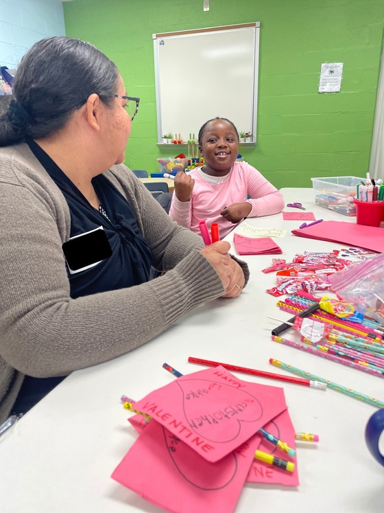 student and parent volunteer making Valentine's cards together
