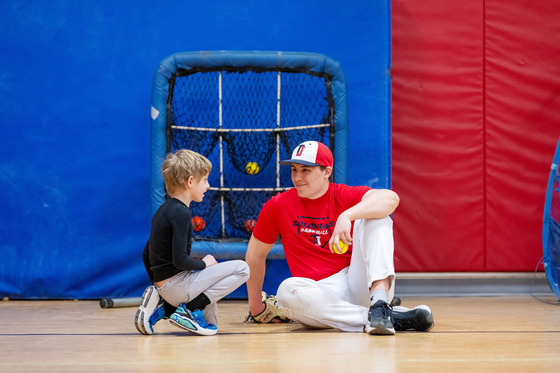 Andrew Haydon sitting next to a child who is participating in his camp.