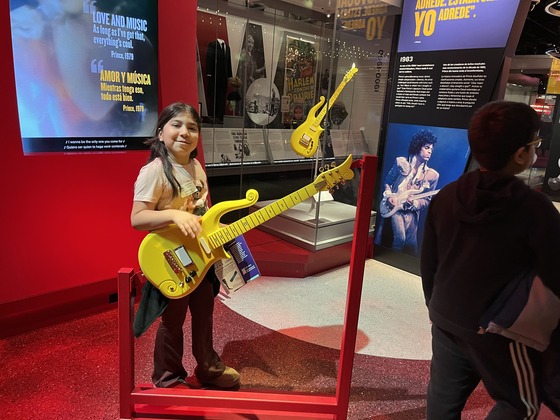 Student holds a guitar at the museum 
