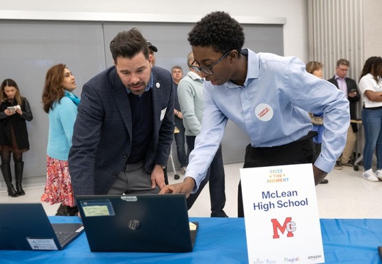 student showing adult something on his laptop