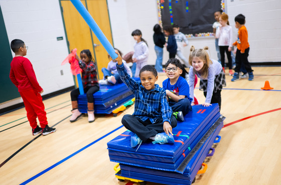 Students sitting on mats while being pushed like in a bobsled