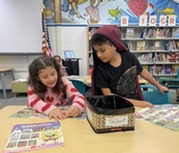 Two students looking through the Book Fair catalog. 