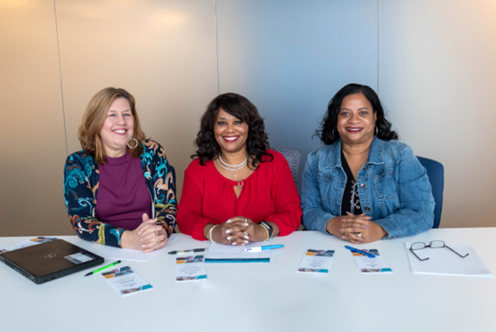 Three women sitting behind table
