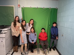 Students in front of a green screen smiling
