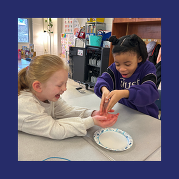two students smile joyously and squeal with glee and shock as they pass an ice cube between each other, trying to melt it quickly