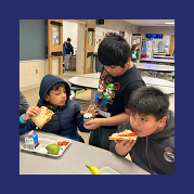 a student hands a cupcake to another student