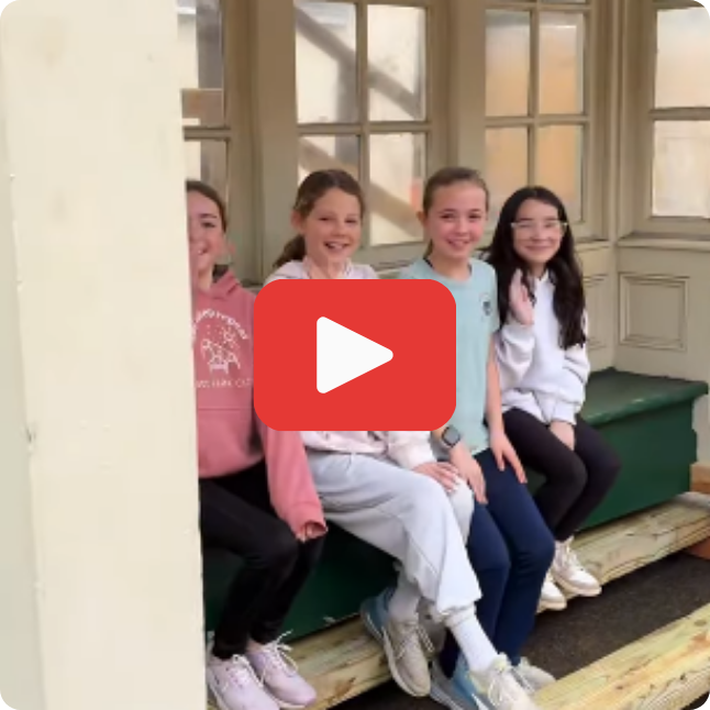 students smiling waiting at a bus stop with a play button on top