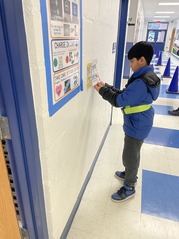 Student hanging up poster. 