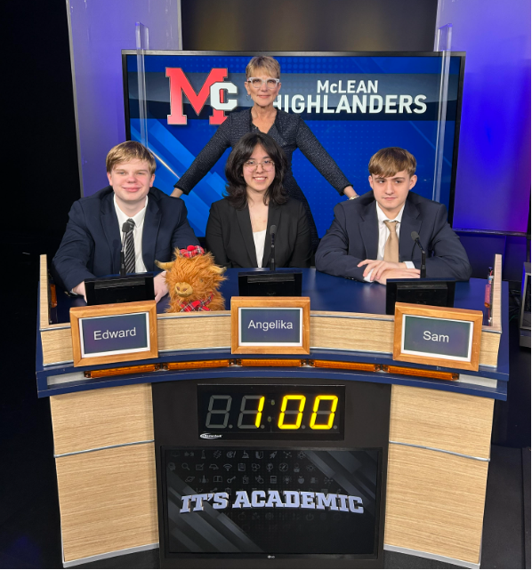 McLean Highlanders team and host posing at the desk on the "It's Academic" game show set