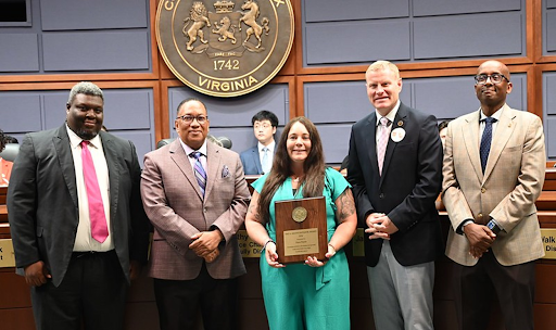 people smile for photo while one person holds an award