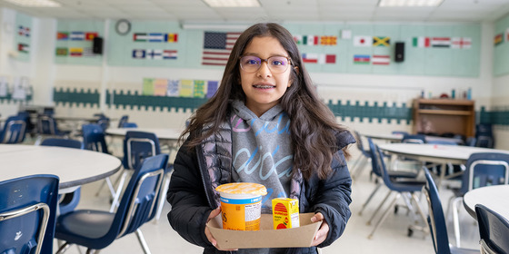 student smiles with their school lunch