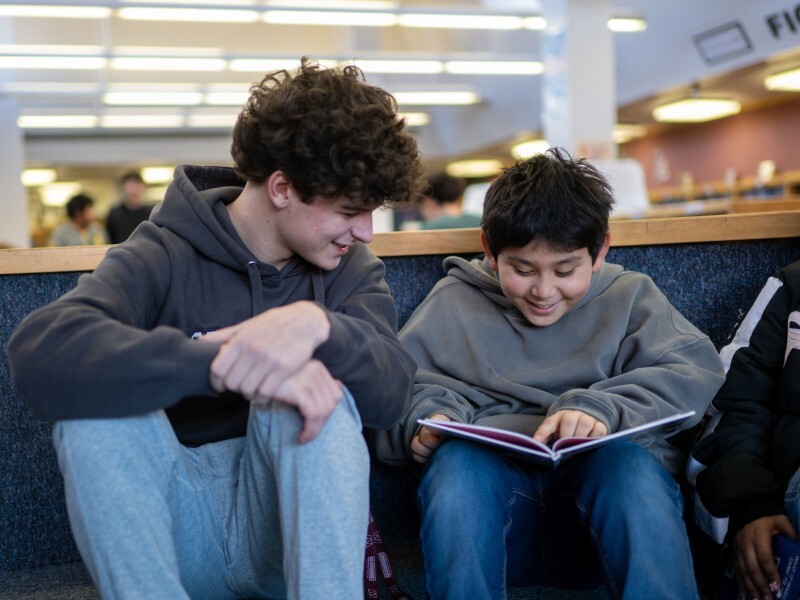 Herndon HS Basketball player reading to Herndon ES student in the library