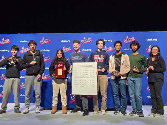 All of the members of TJ's state championship Scholastic Bowl team standing in a line holding the trophy they won.