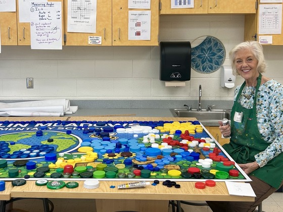 Volunteer Sue Conway gluing down donated bottle caps for our bottle cap mural.