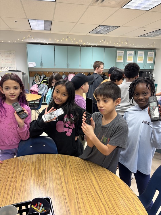 3rd graders modeling old cell phones