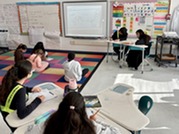 Students on the carpet looking at their teacher's model of the ocean floor. 