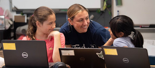 adult smiles at students