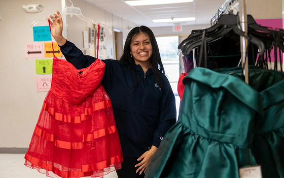 student holds up prom dress at the prom dress shop
