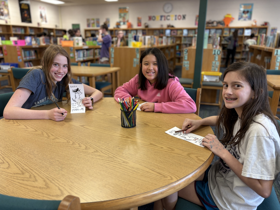 students sit together coloring bookmarks in library 