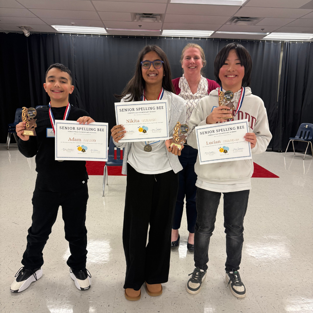 Three students stand on stage in front of the school principal, holding certificates and trophies