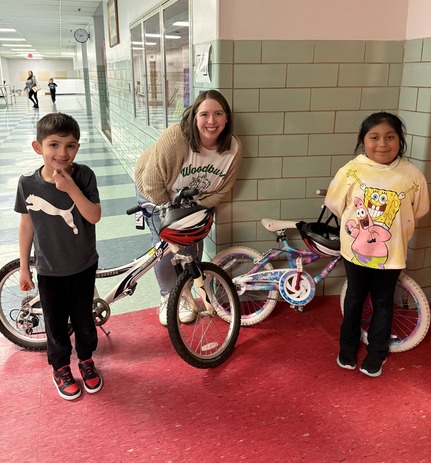 A boy, a girl, and Ms. Dauberman stand with two bikes 