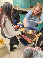 Student and teacher planting grass seeds in container
