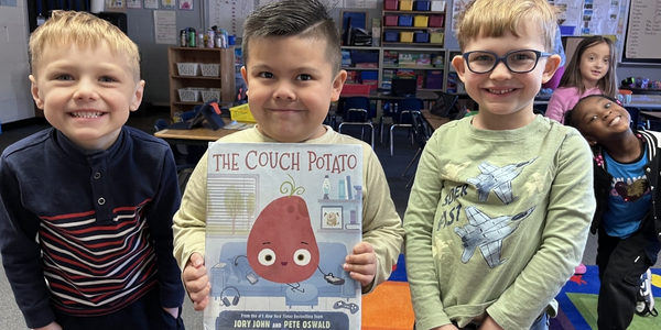 Three students, one holding a book "The Couch Potato"