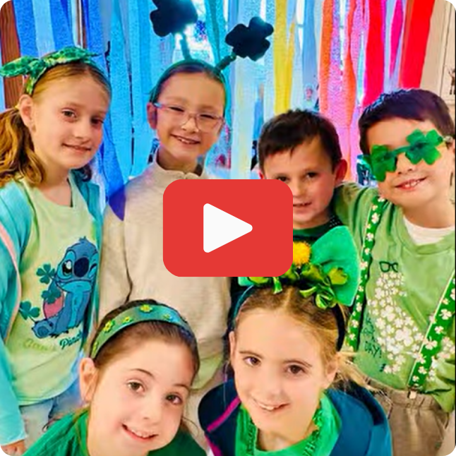smiling students wearing green with red and white play button on top of image