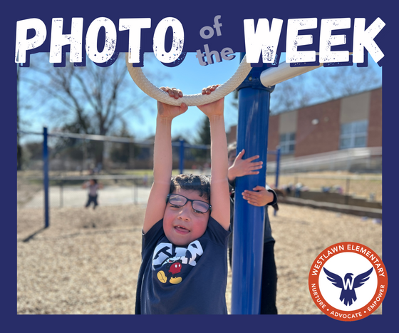 Photo of the Week: a student hangs from the hanging bars on the play structure on a beautiful day