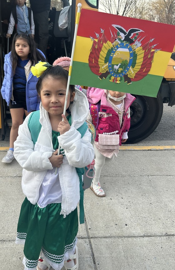 A student holding a flag that represents their family's culture.
