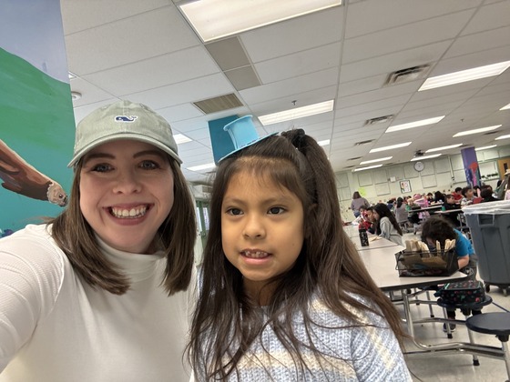 A student smiles with a teacher in hats for hat day 
