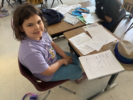 A student smiles with her work 