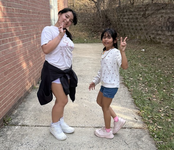 Two girls turn and smile while running outside 