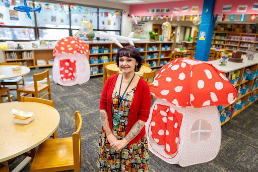 librarian smiles for a photo in the library with mushroom tents behind her