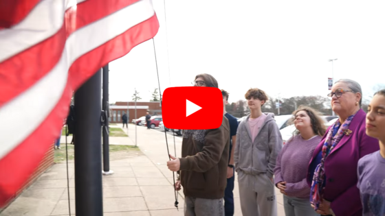 A screenshot of a video where Dr. Reid and students watch a flag being raised.