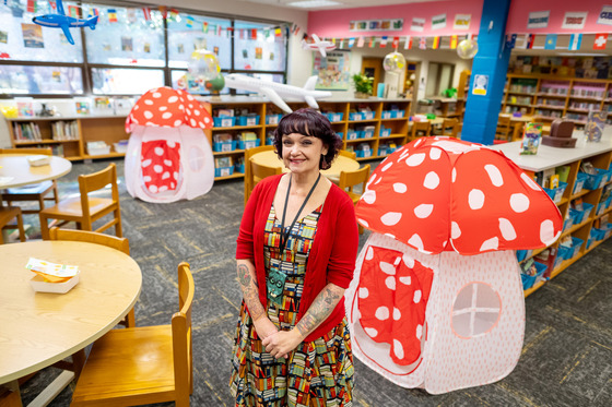 A woman stands in a library decorated with mushroom tents