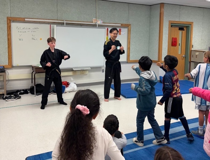 A student and tae kwondo instructor show 2nd graders some moves 