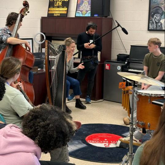 Students playing instruments together with adult teaching