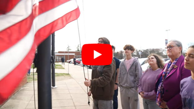 Dr. Reid and students standing watching flag being raised