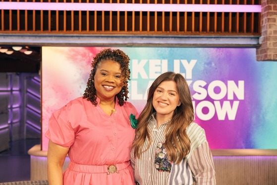 teacher smiles next to Kelly Clarkson on the set of her TV show