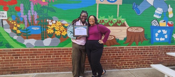 two FCPS employees smile with an award