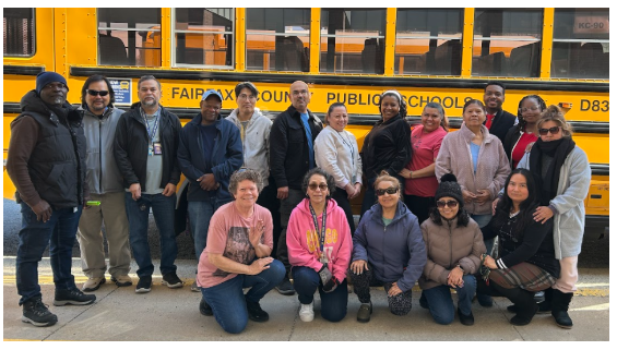 bus drivers and attendants standing and sitting in front of the school bus