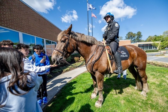 students feed a police horse in front of a school