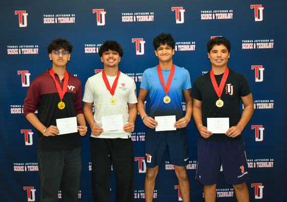 Four TJ Students show off their medals for being named National Merit Scholar Commended students while standing against a TJ logo backdrop.