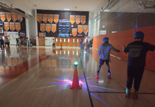 students rollerskating in a dark gym