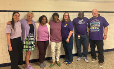 staff in a line wearing purple