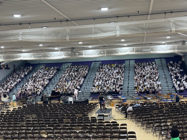 Full bleachers in school of all county chorus singers.