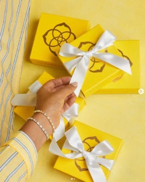 a hand modeling jewelry with gift boxes in the background